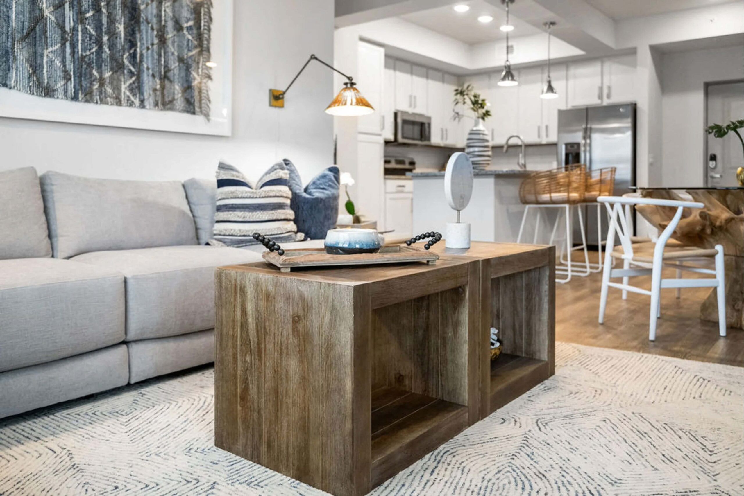 Inspira Naples Modern living room with a wooden coffee table, gray sofa, and open kitchen in the background.