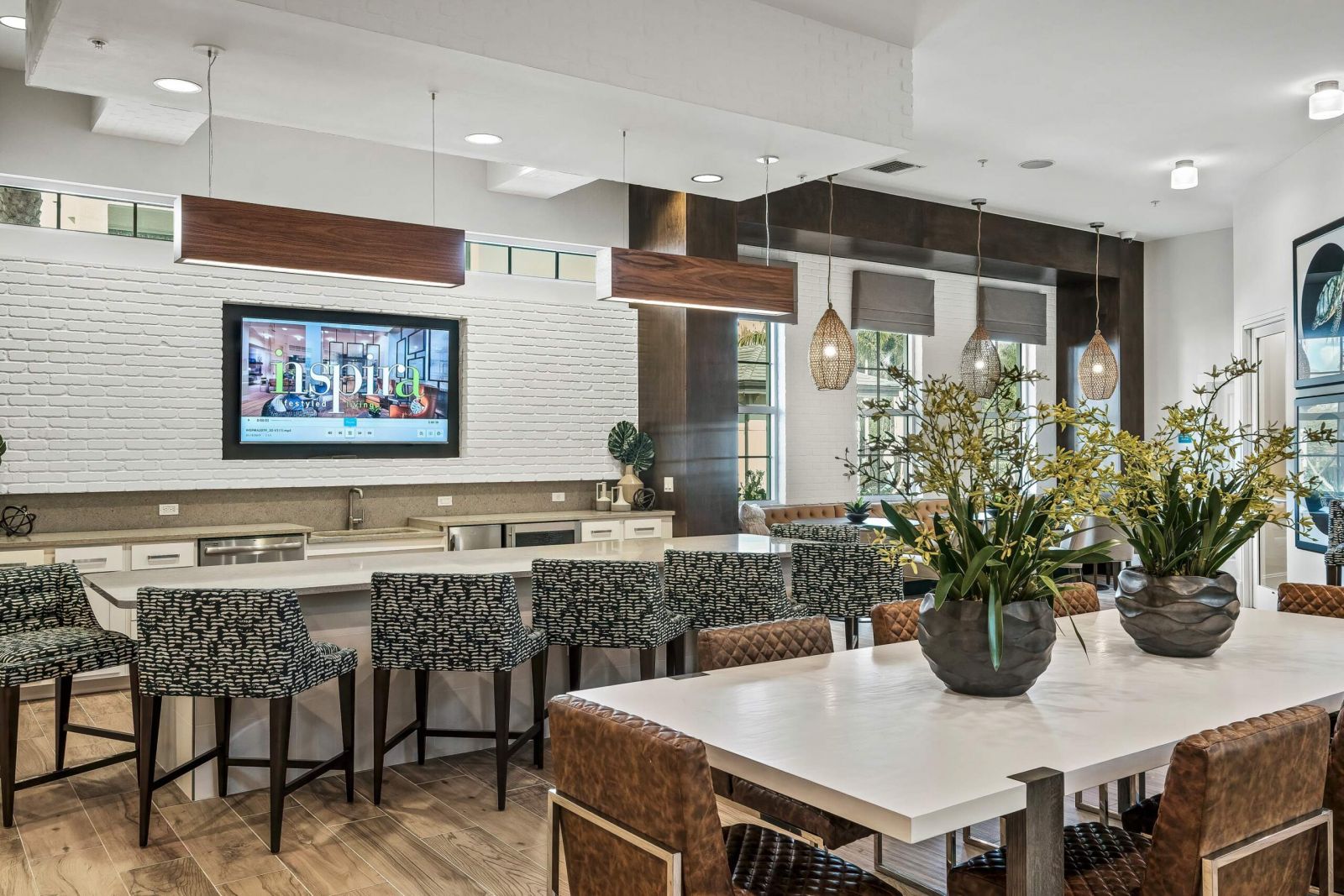 Inspira Naples Modern communal kitchen and dining area with bar stools, contemporary lighting, and decorative plants.